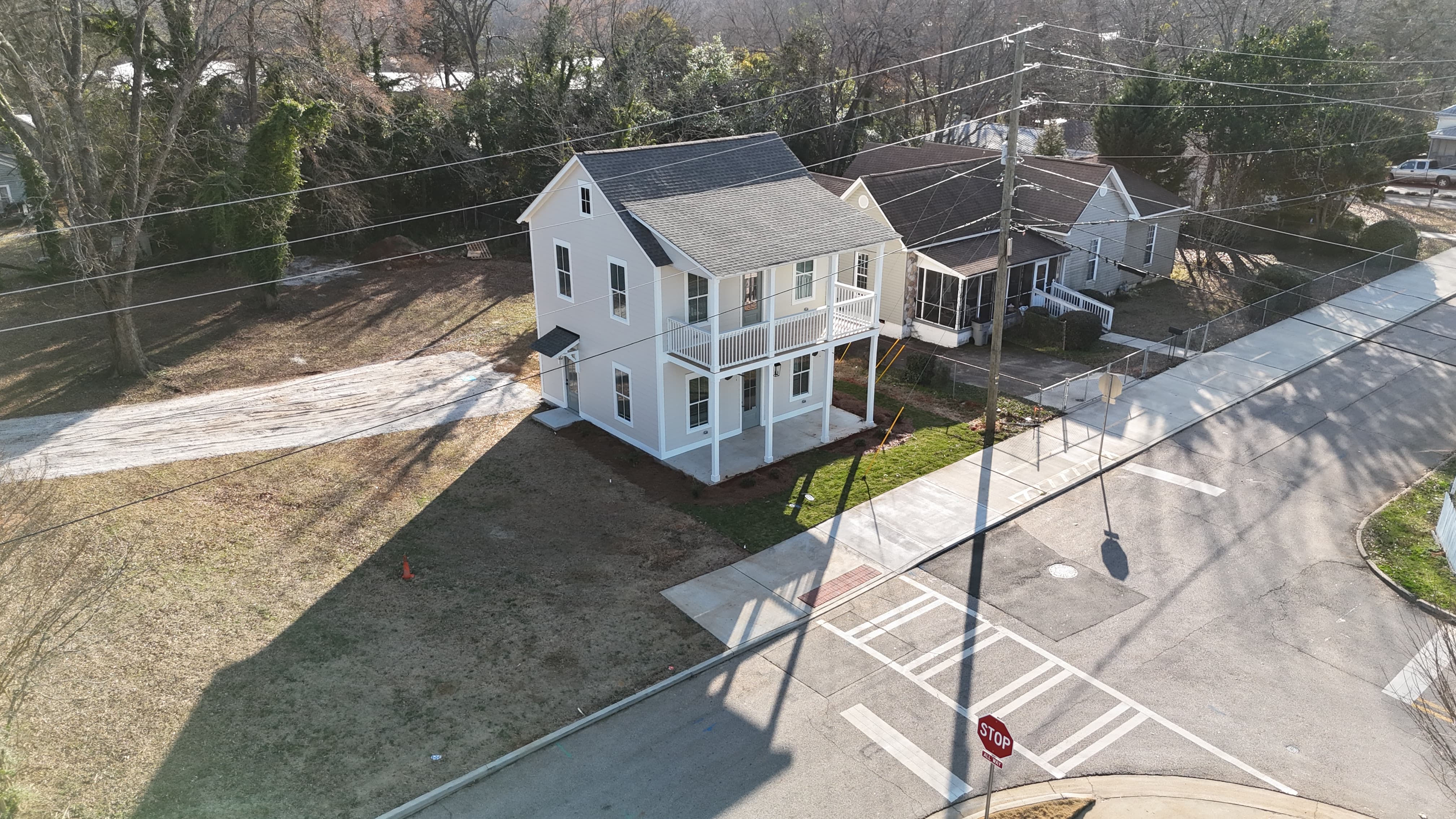 Two-story gray house with white trim, a front porch, and a landscaped front yard on a sunny day.