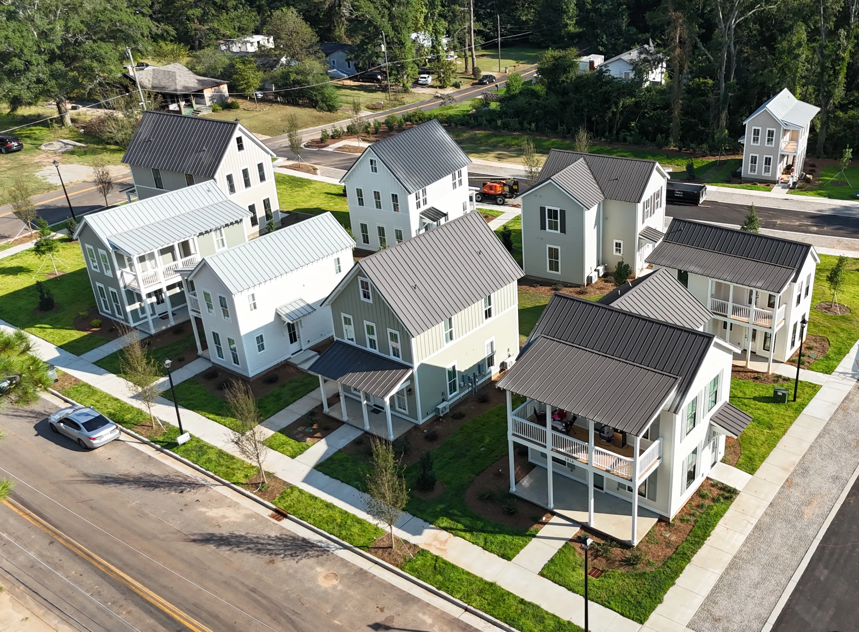 Two-story gray house with white trim, a front porch, and a landscaped front yard on a sunny day.