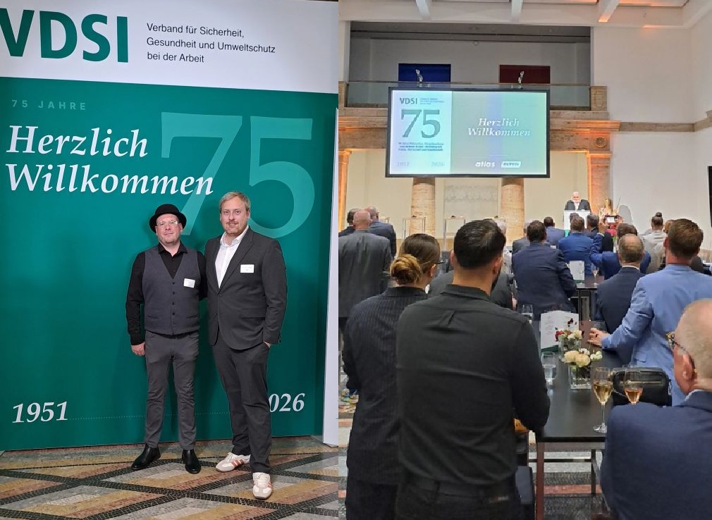 Jubiläumsveranstaltung zum 75-jährigen Bestehen des VDSI in Berlin. Zwei Teilnehmer stehen vor einer VDSI-Fotowand, während im Veranstaltungsraum Gäste einer Rede folgen.