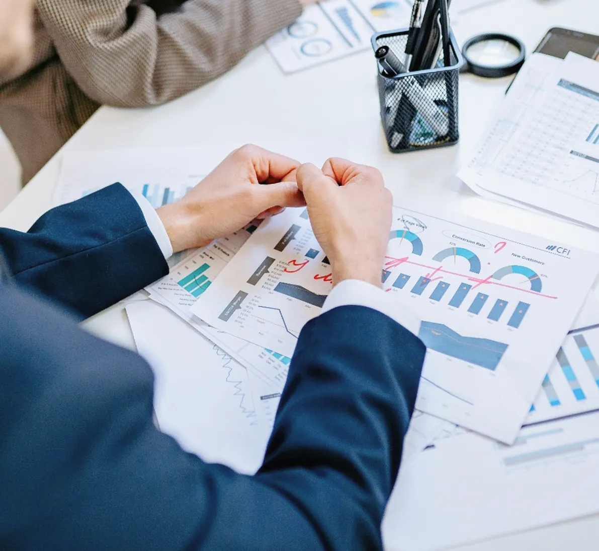 Person in business attire reviewing printed financial charts and graphs on a desk.