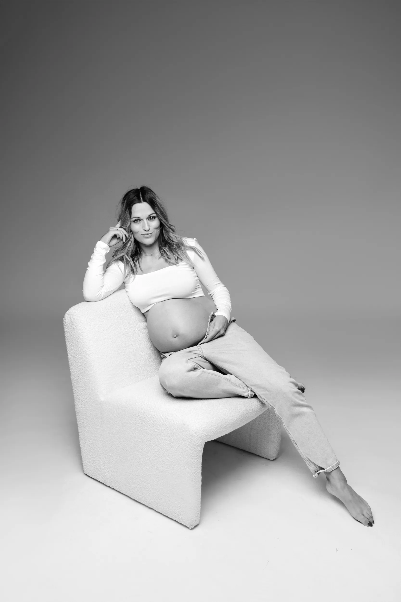 Stylowa fotografia ciążowa – przyszła mama pozująca na designerskim fotelu, Wrocław.