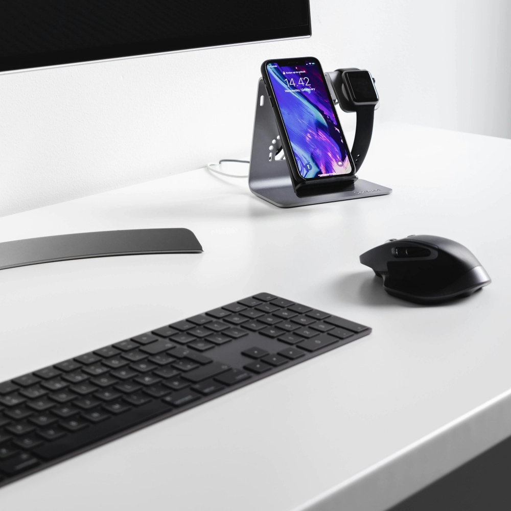 Minimalistický pracovný stôl s klávesnicou, myšou a mobilným zariadením v stojane, znázorňujúci technickú podporu, dostupnosť a priebežnú starostlivosť počas spolupráce.