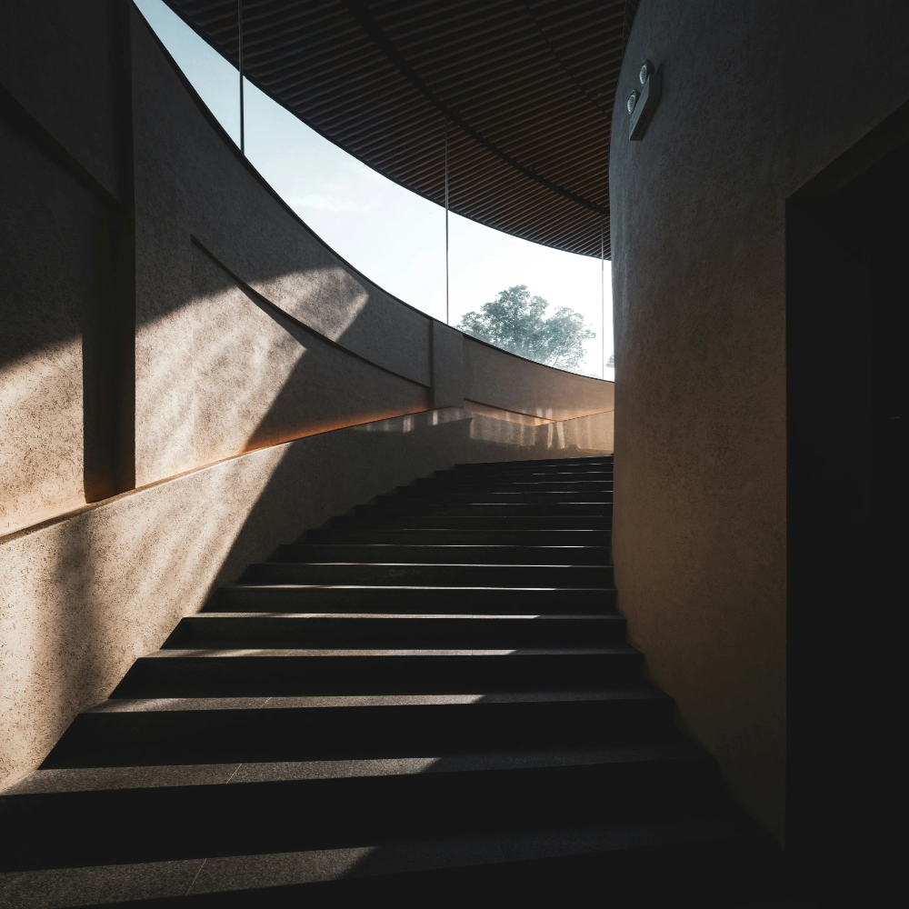 Minimalistické betónové schodisko so svetlom a tieňmi smerujúcimi nahor.