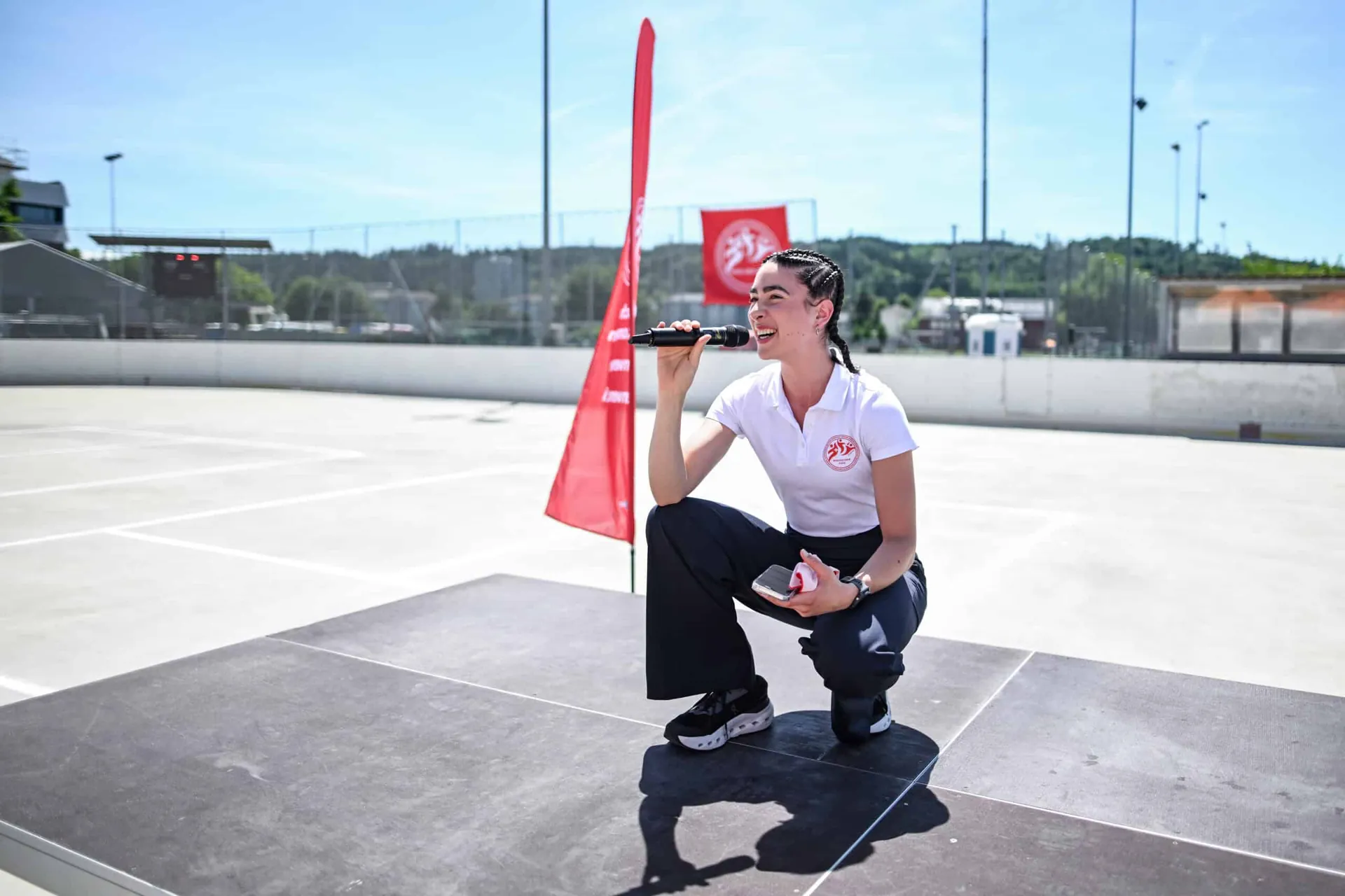 Ladina Ziani speaking on stage at an outdoor sports event