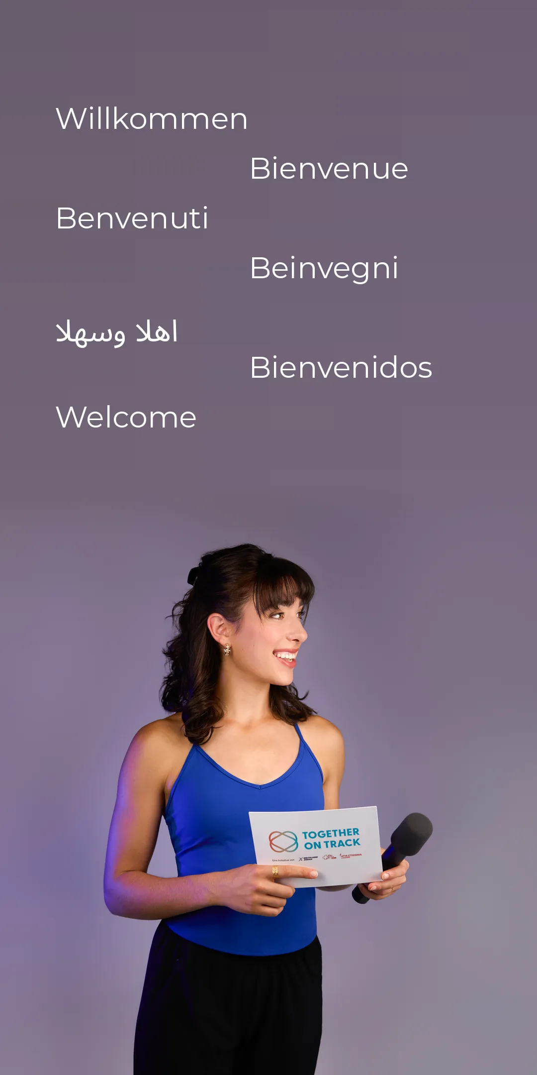Ladina Ziani with a microphone and a moderation card, greeting in seven languages: Willkommen, Bienvenue, Benvenuti, Beinvegni, Ahlan wa sahlan, Bienvenidos, Welcome