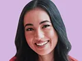 Smiling young woman with long dark hair against a purple background.
