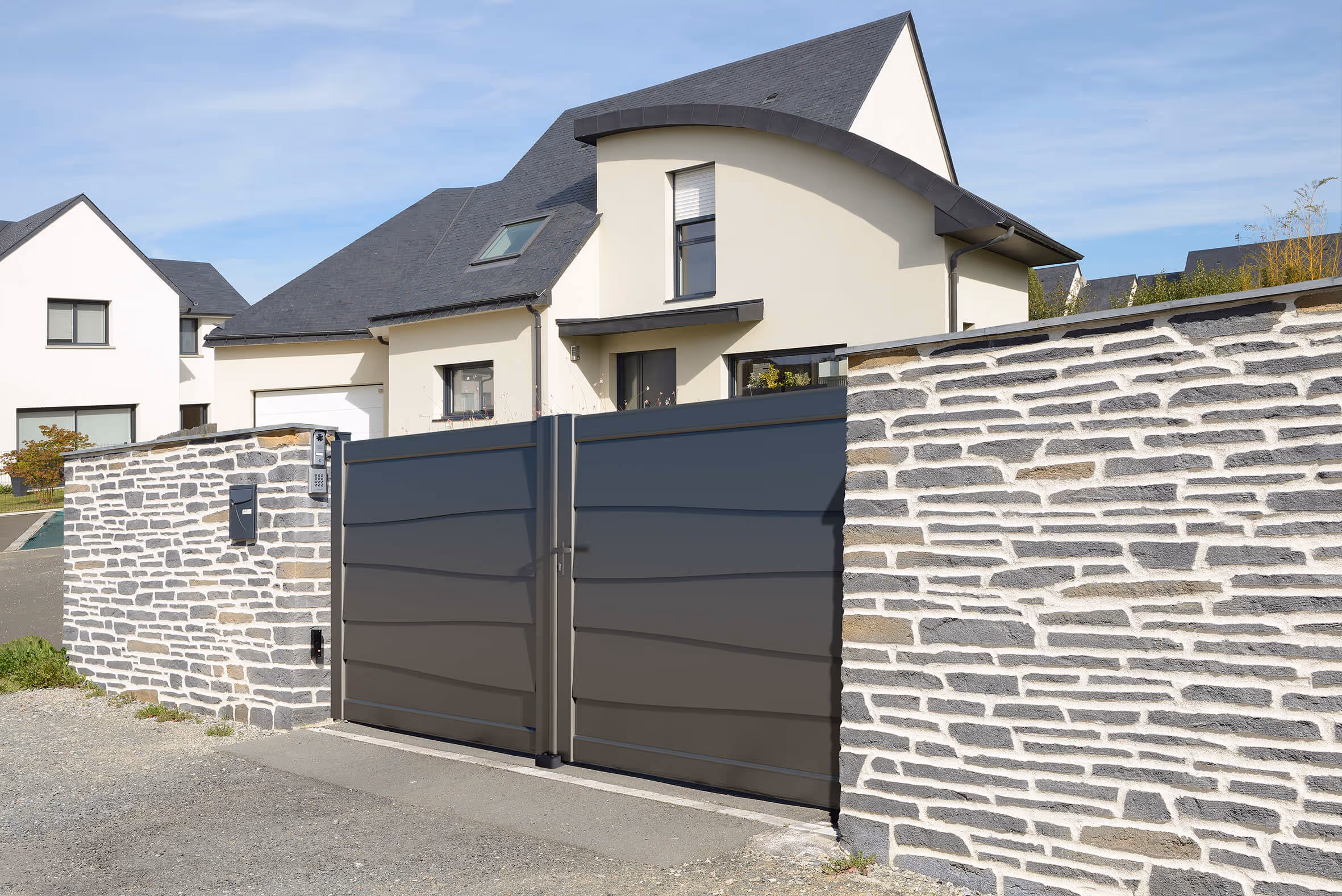 Entrée d'une maison moderne avec portail double gris mat et mur en pierre apparente.