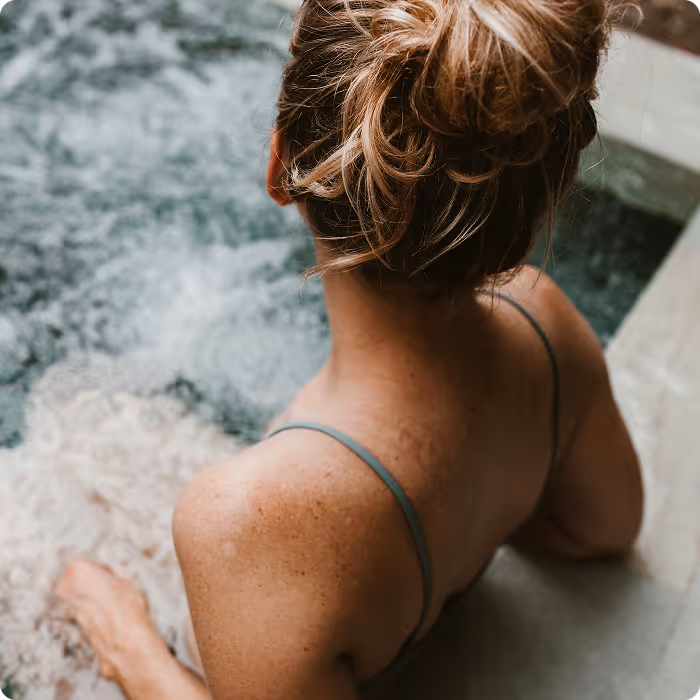 Woman with blonde hair in a bun relaxing in a bubbling hot tub.
