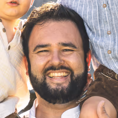 Smiling bearded man with two children partially visible on each side.