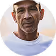 Portrait of an elderly man wearing a dark cap and a white t-shirt.