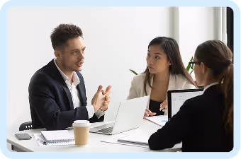 Three professionals having a meeting around a table with laptops and coffee cup.