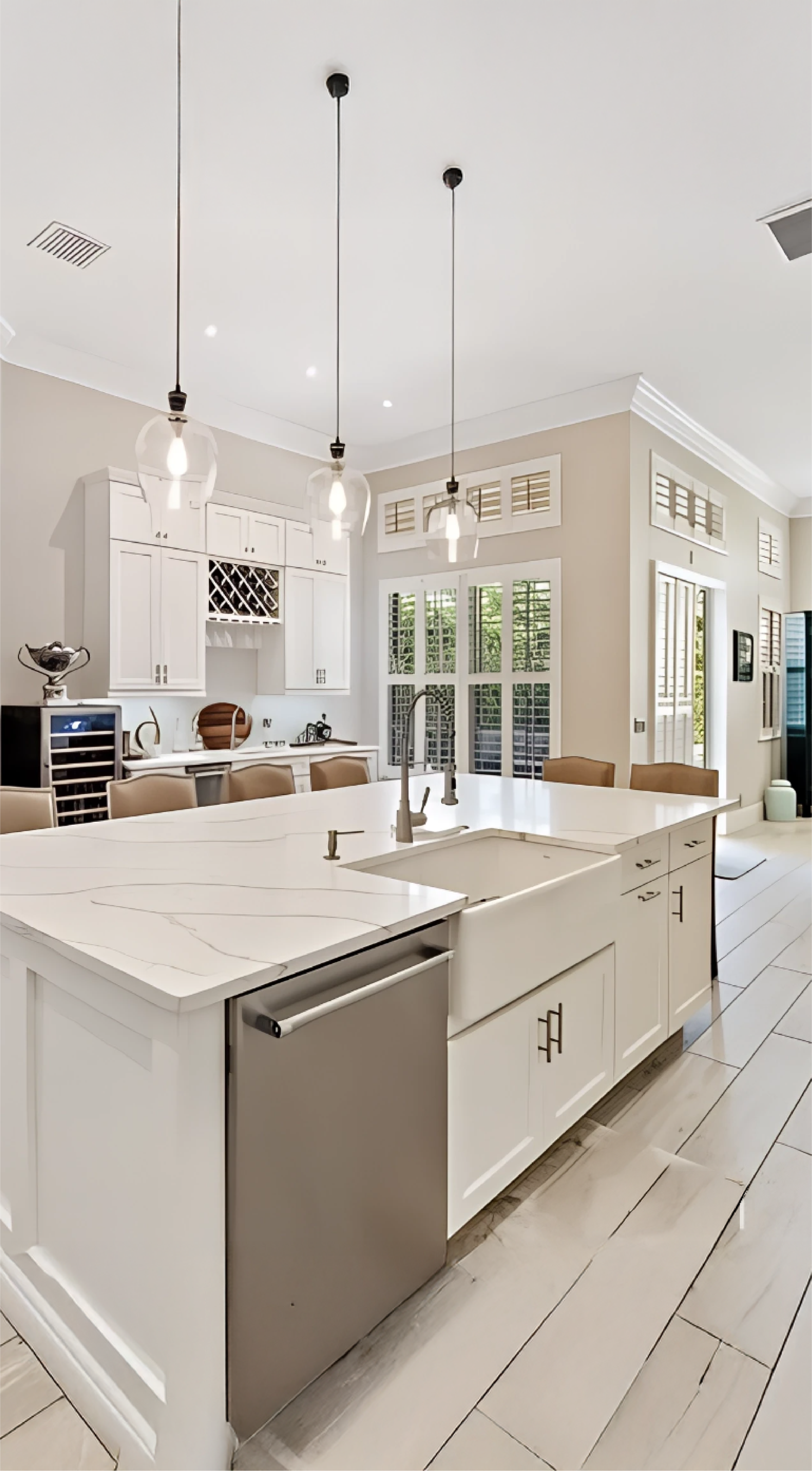 Modern white kitchen with custom cabinetry by Gonzo Interiors, featuring a marble island, farmhouse sink, and elegant pendant lighting.
