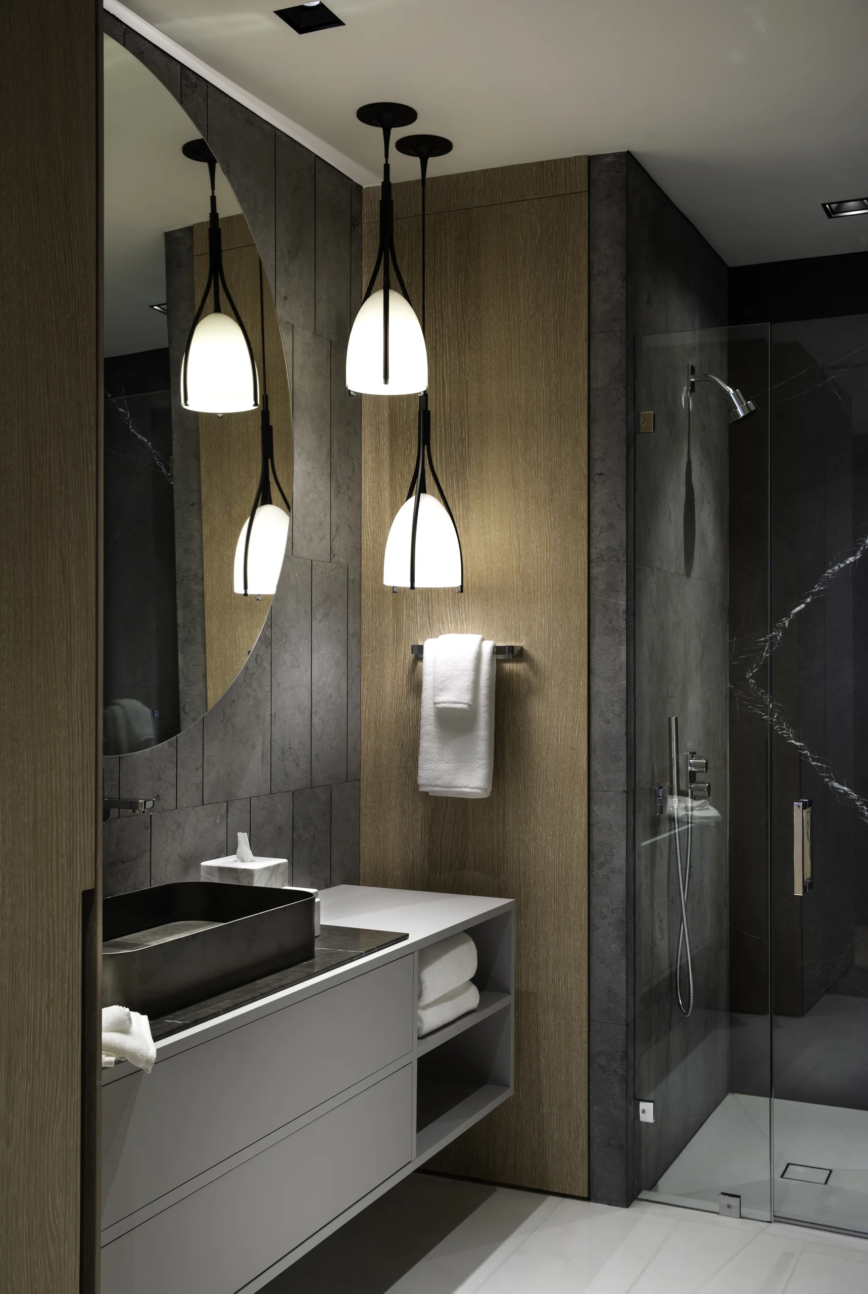 Guest bathroom with a curved mirror, pendant lighting over the vessel sink, and a glass-enclosed shower, Star Island Waterfront project by Dunagan Design.