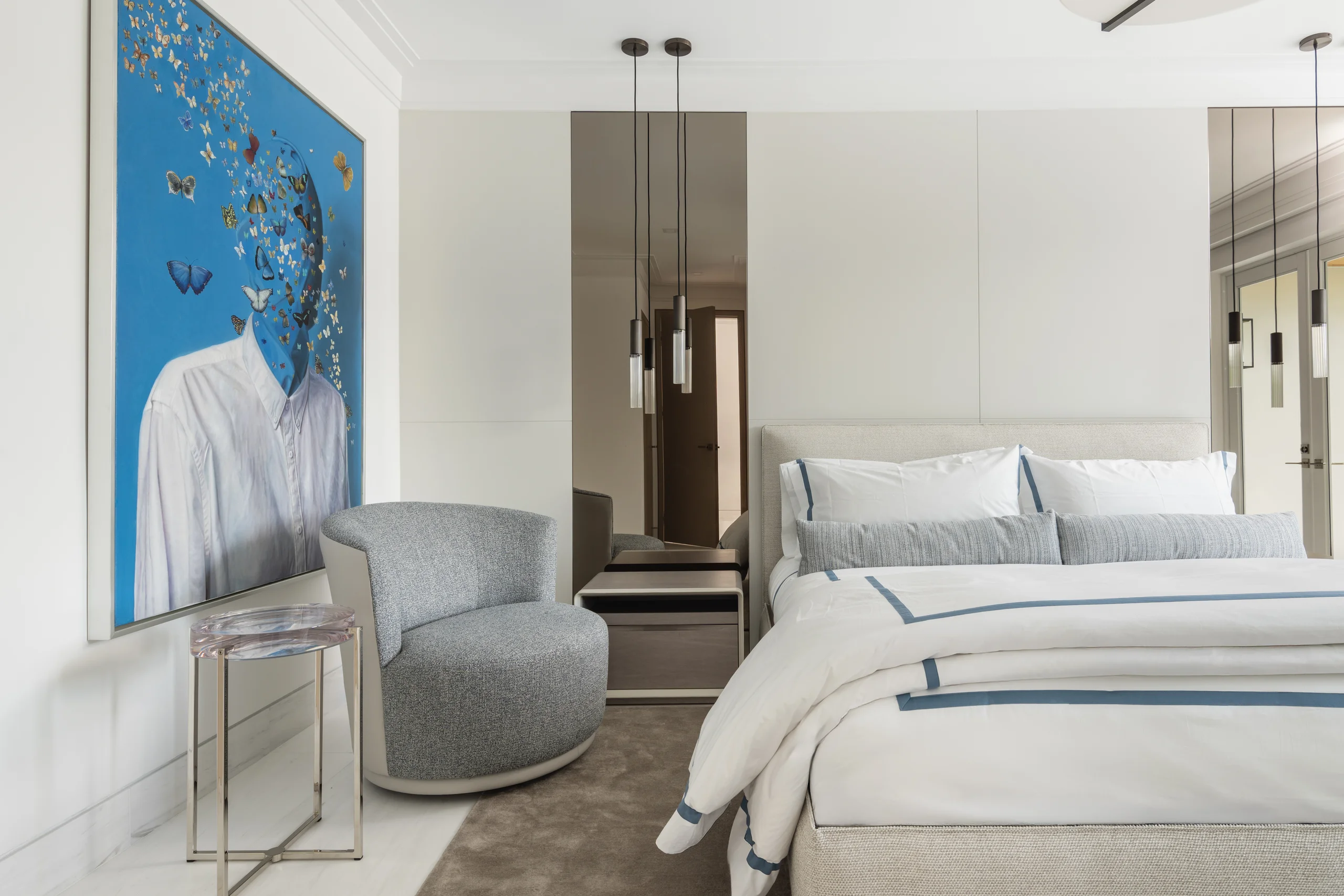 Guest bedroom with an upholstered headboard, pendant lighting, and a whimsical portrait painting, Coco Plum Revival project by Dunagan Design.