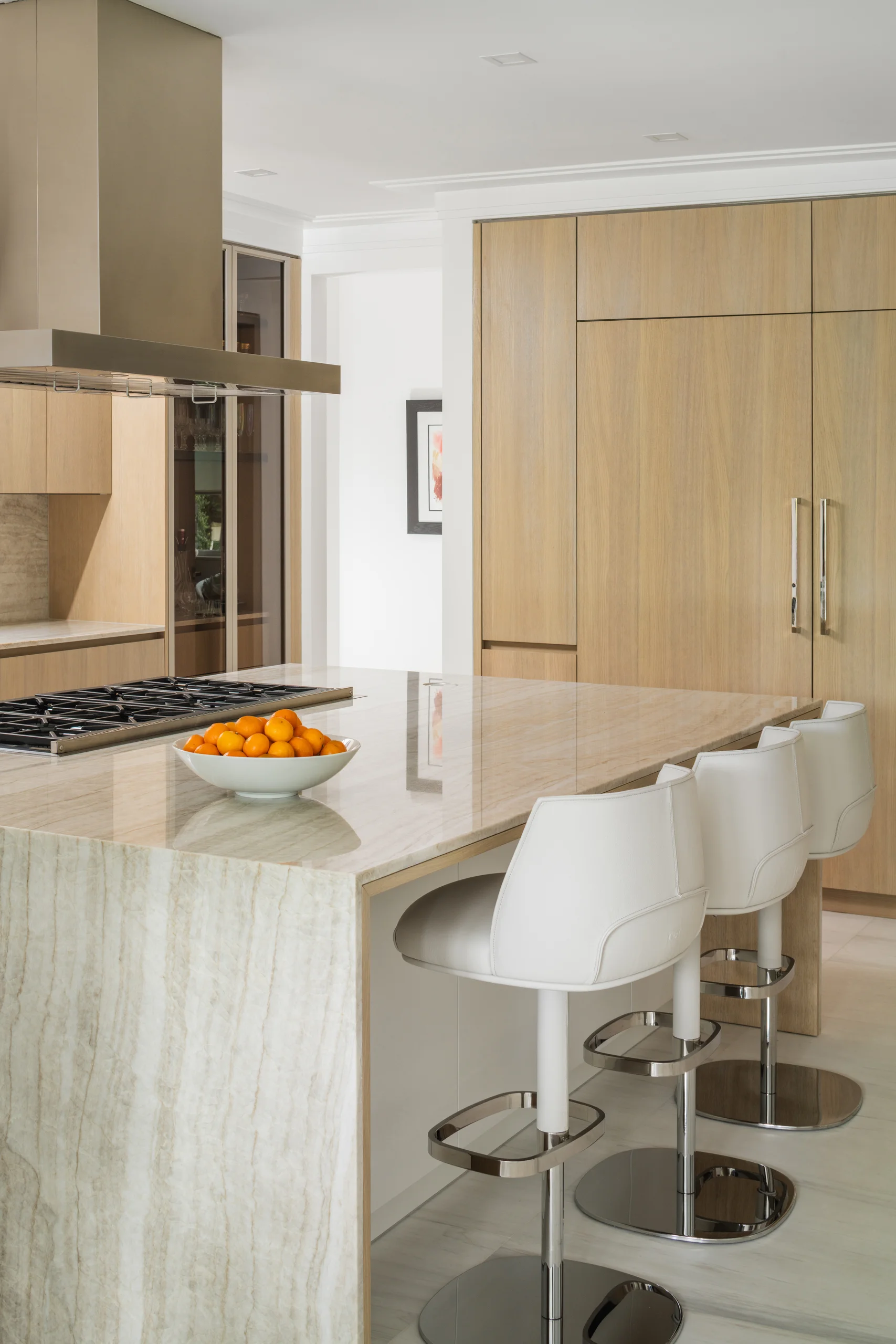 Kitchen island with white swivel counter stools and book-matched stone countertops, Coco Plum Revival project by Dunagan Design.