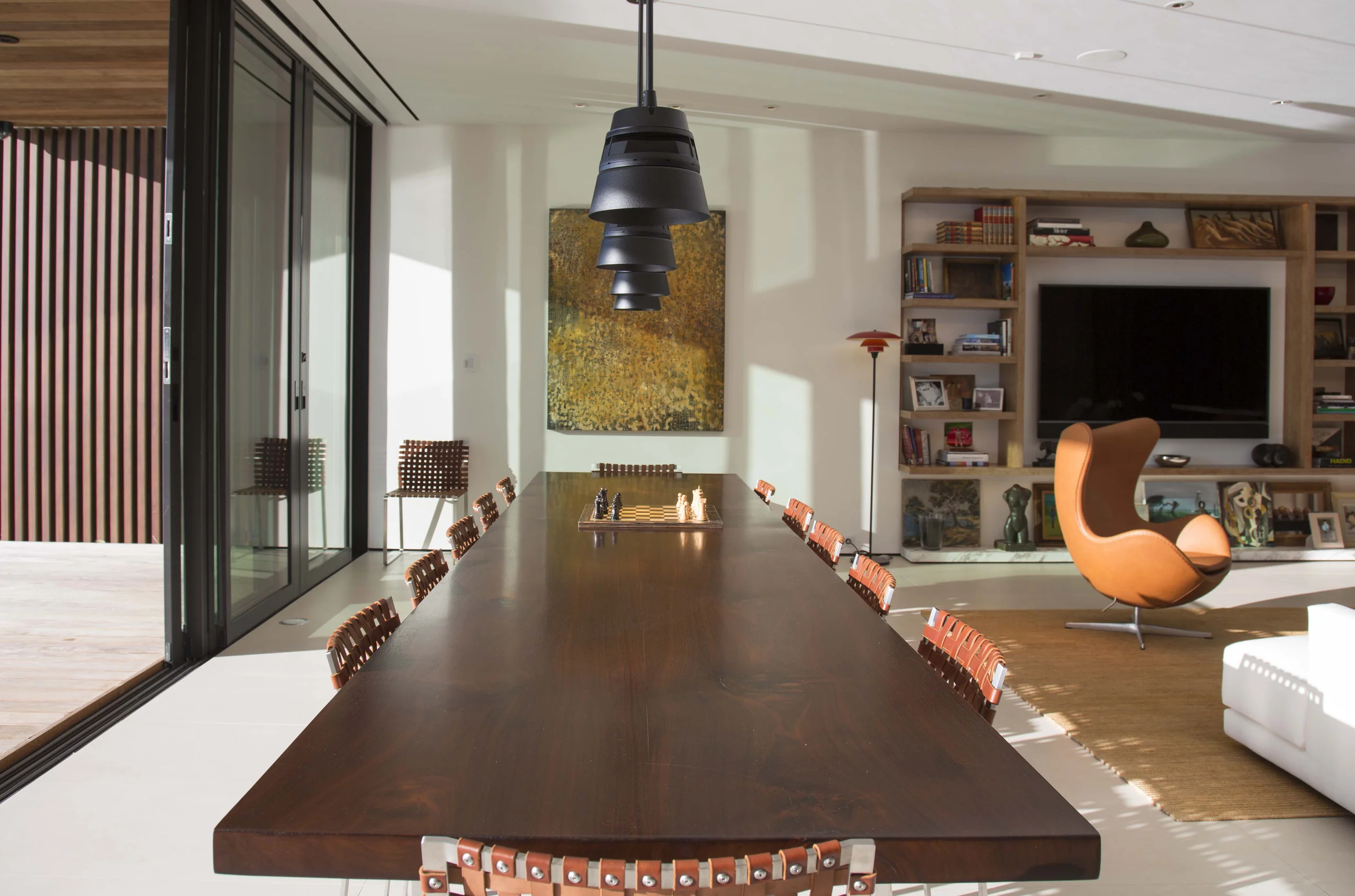 Dining room with a live-edge walnut table, woven leather chairs, and a sculptural black pendant, Bayside Modern project by Dunagan Design.