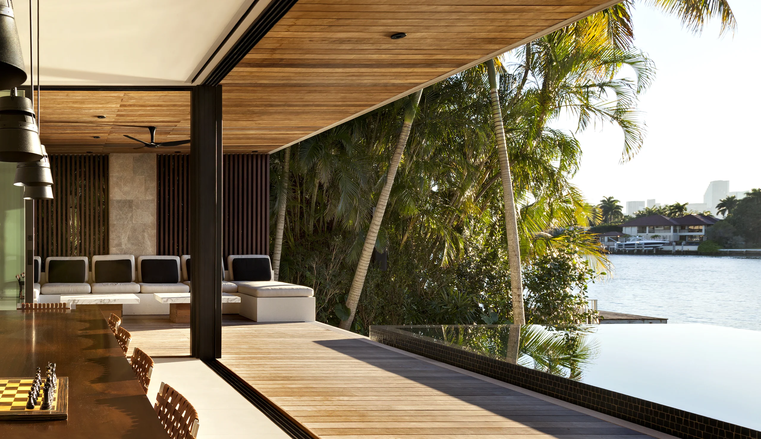 Covered outdoor terrace with sectional lounge seating overlooking the infinity-edge pool and bay, Bayside Modern project by Dunagan Design.