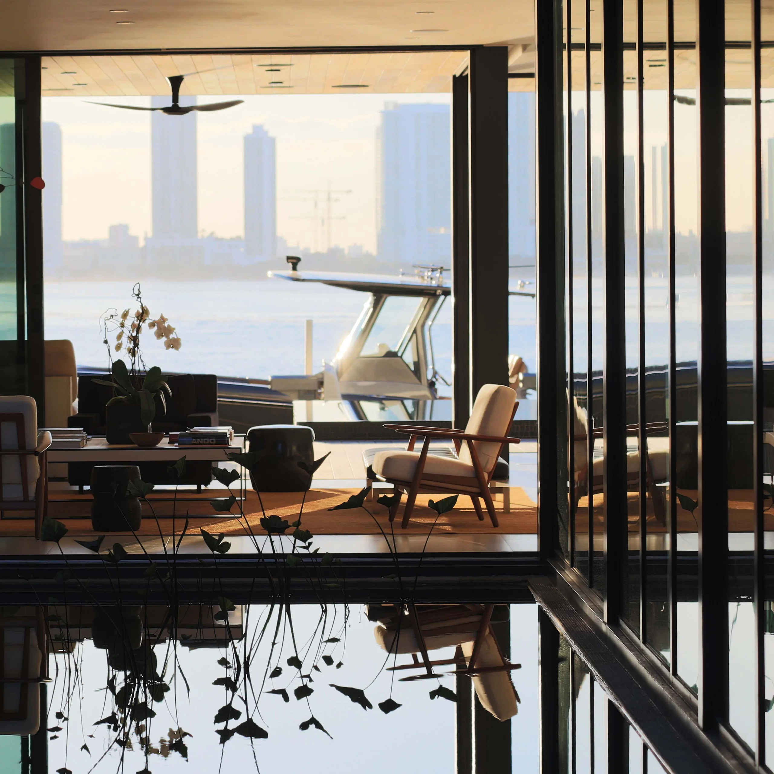 Living room framed by a reflecting pool with views to the boat dock and Miami skyline at sunrise, Bayside Modern project by Dunagan Design.