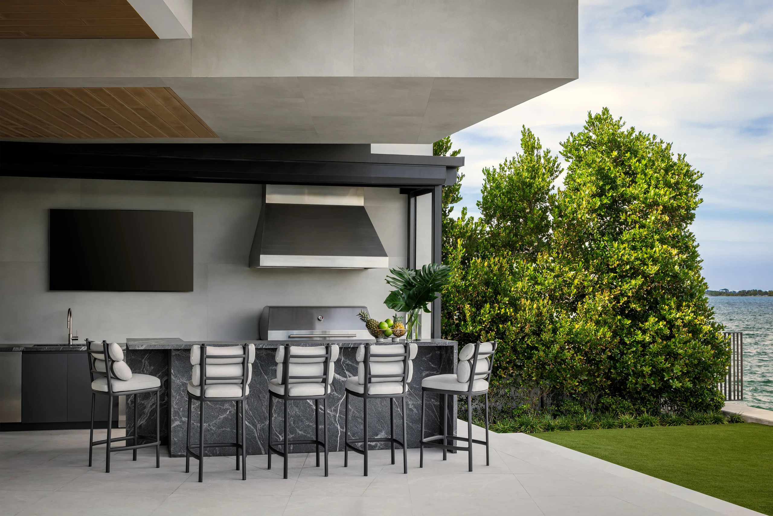 Outdoor kitchen and lounge with a mounted TV and bay views beyond, San Marino Gallery project by Dunagan Design.