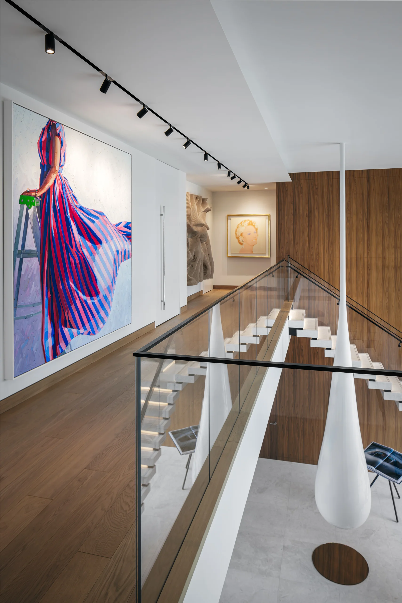 Upstairs gallery hallway displaying curated artwork alongside a floating staircase, San Marino Gallery project by Dunagan Design.