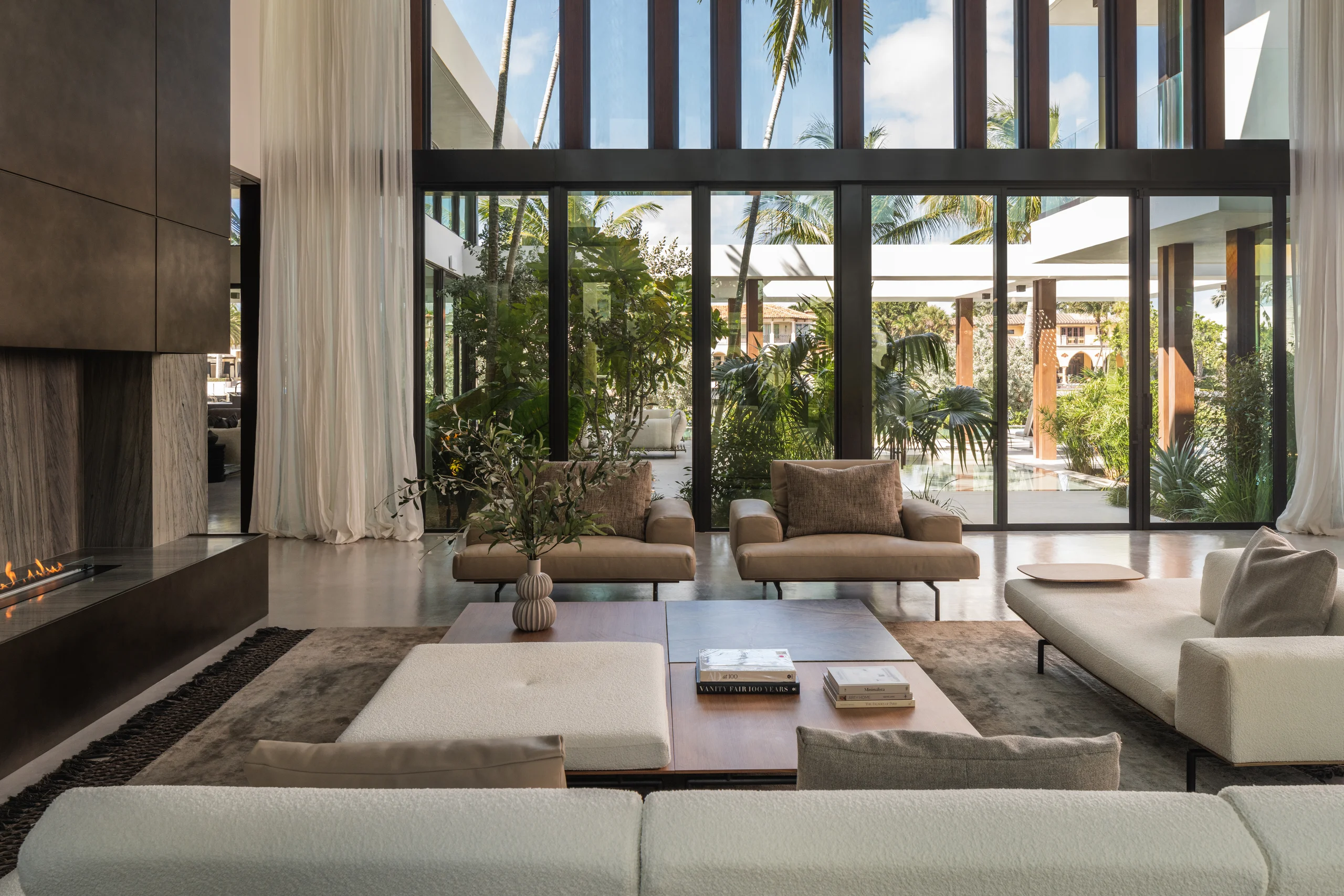 Living room opening through a wall of glass to a lush landscaped courtyard, Spanish River Modern project by Dunagan Design.