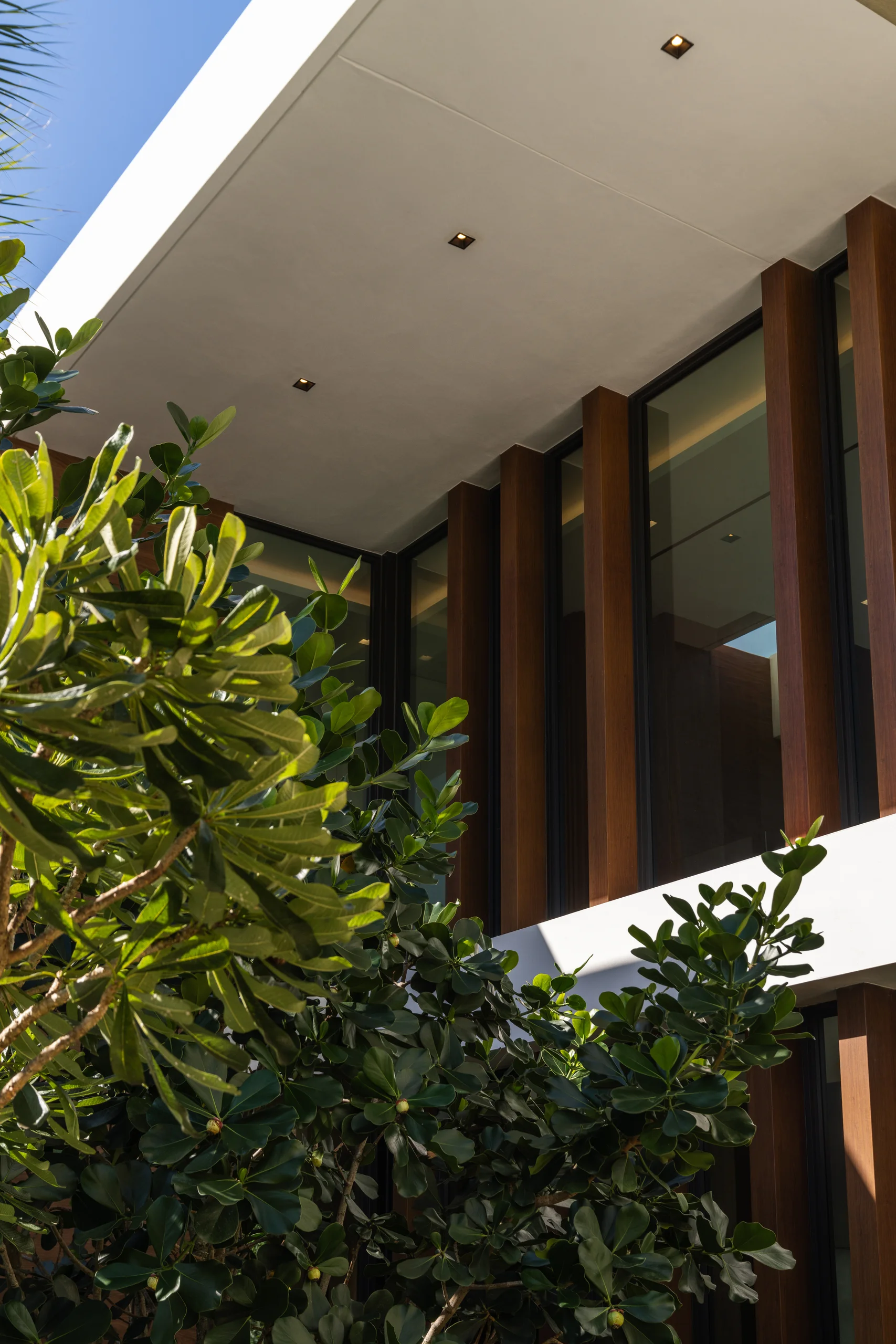 Exterior architectural detail of a wood-fin facade with a cantilevered white roof, Spanish River Modern project by Dunagan Design.
