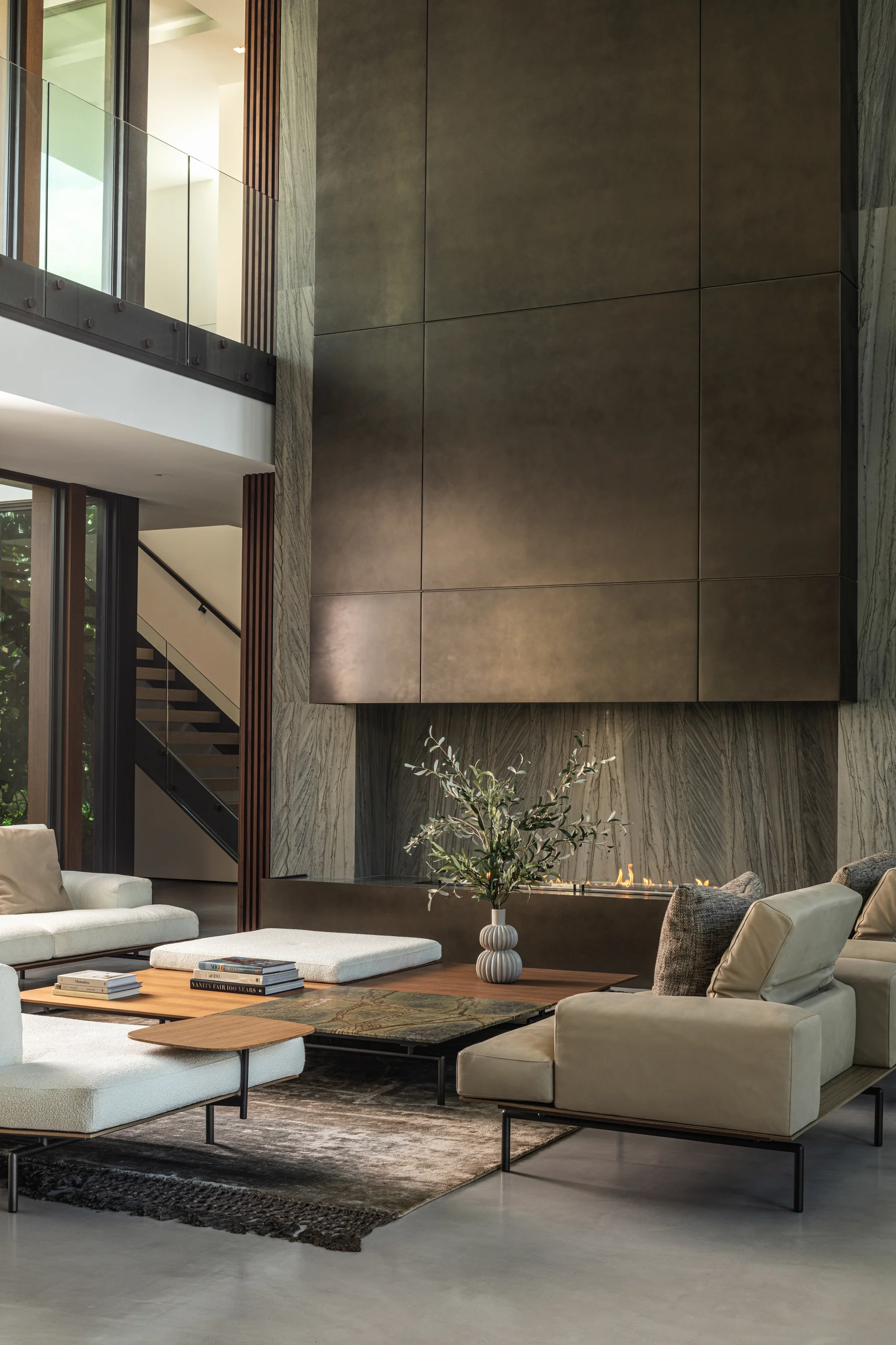 Double-height living room with a bronze-paneled fireplace wall and a mix of upholstered seating, Spanish River Modern project by Dunagan Design.