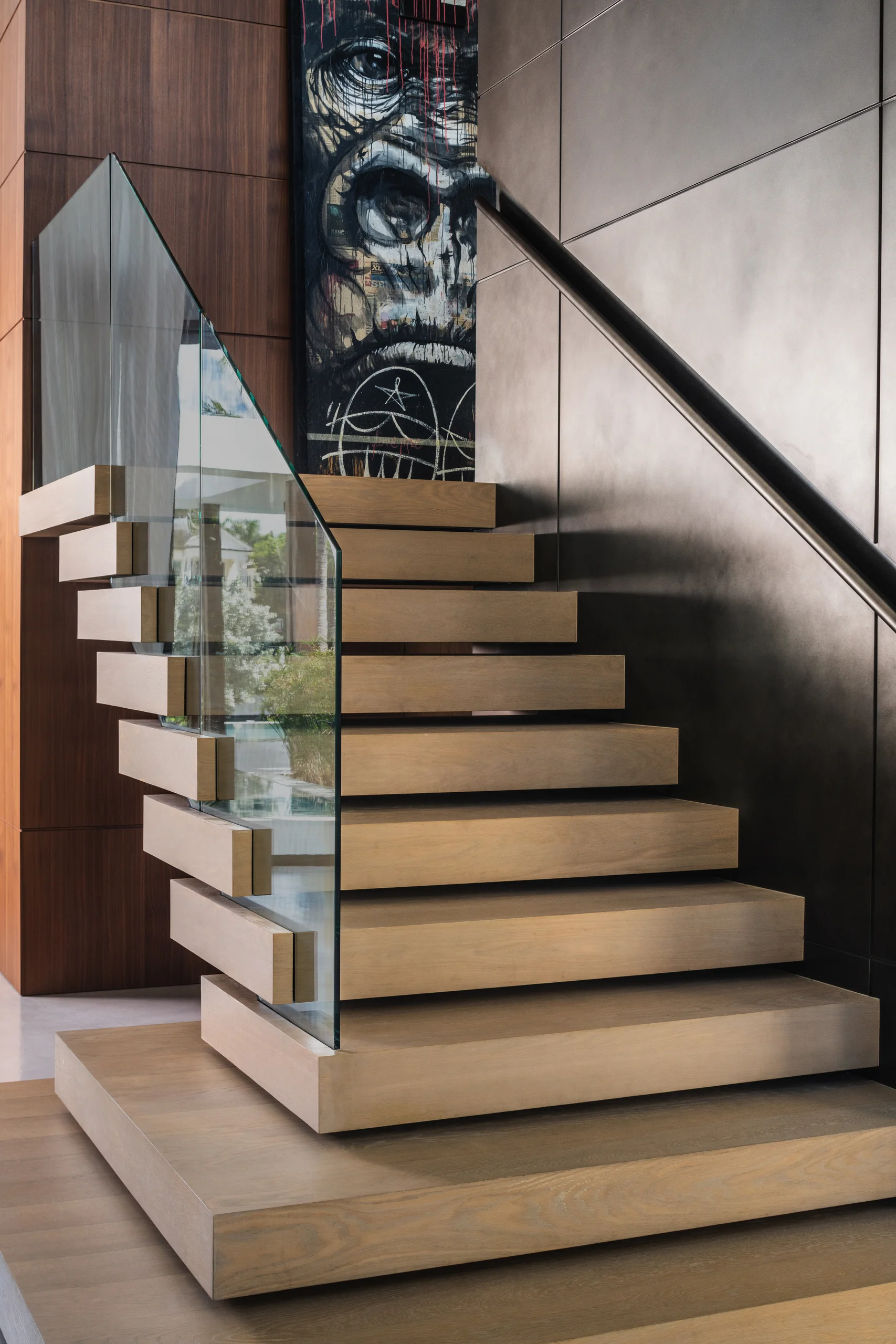 Floating oak staircase with a glass railing beside a large-scale figurative painting, Spanish River Modern project by Dunagan Design.