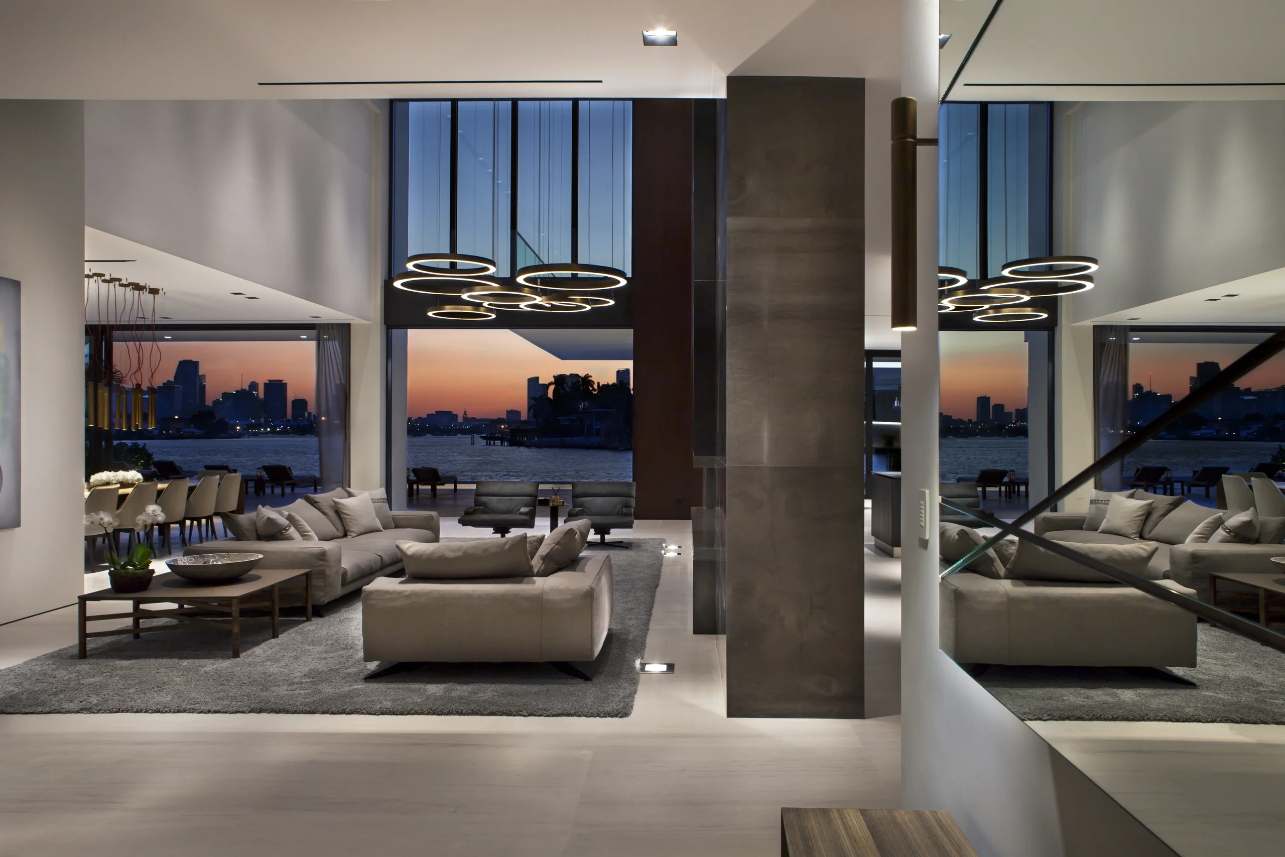 Living room with floor-to-ceiling glass framing a twilight view of the Miami skyline, DiLido Modern project by Dunagan Design.