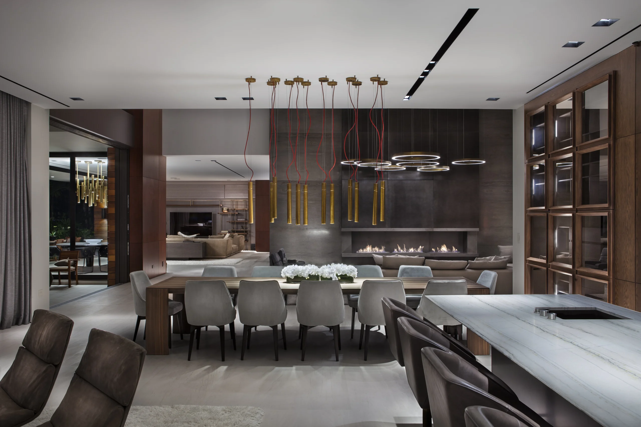 Dining room at dusk beneath a dramatic brass pipe pendant fixture, DiLido Modern project by Dunagan Design.