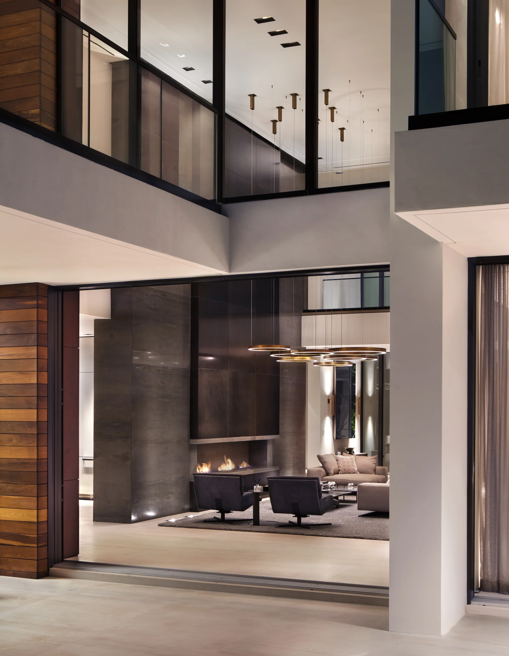 Glass entry pavilion at night opening to a fireplace lounge beyond, DiLido Modern project by Dunagan Design.