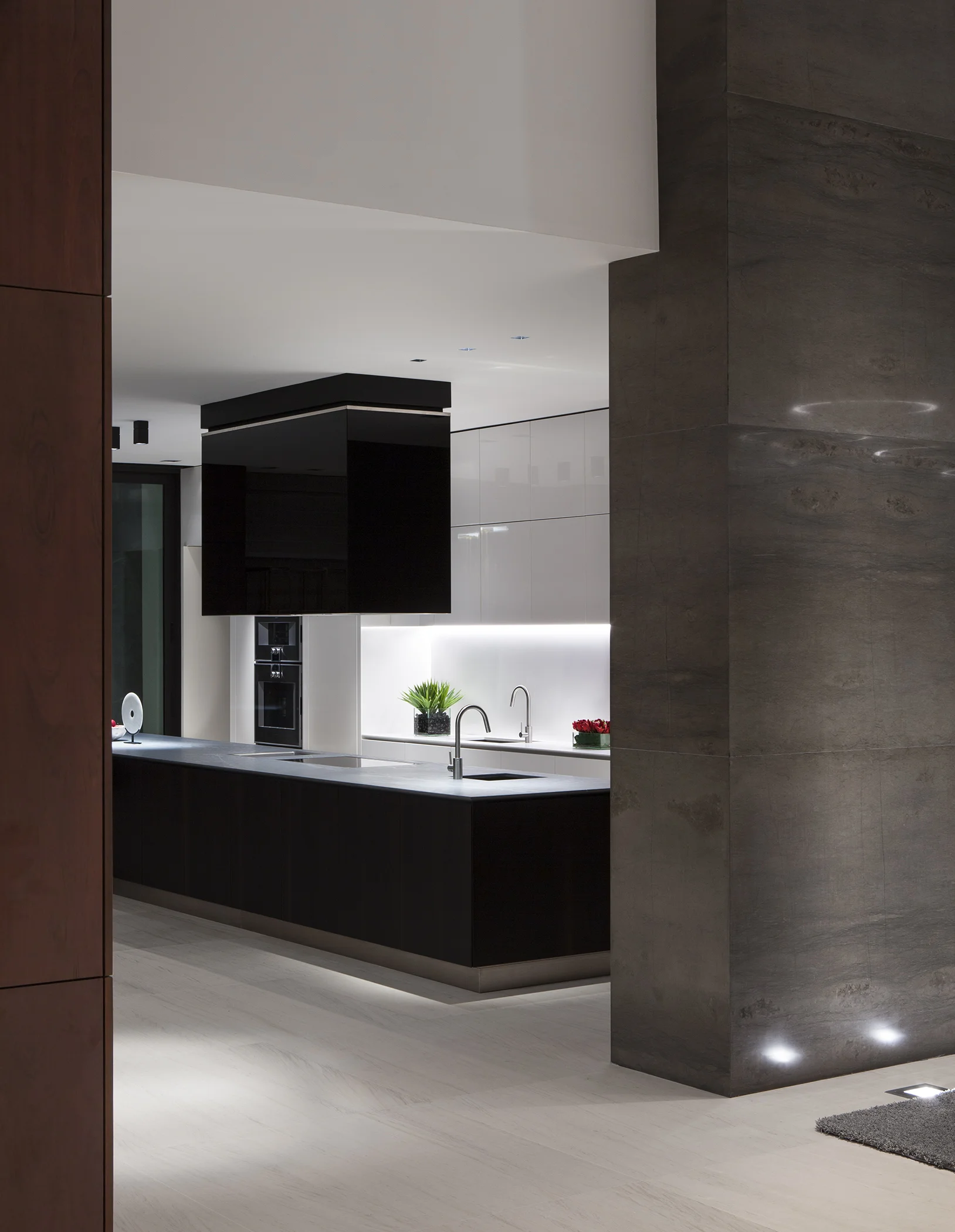 Kitchen with a black waterfall island framed by a stone-clad column, DiLido Modern project by Dunagan Design.