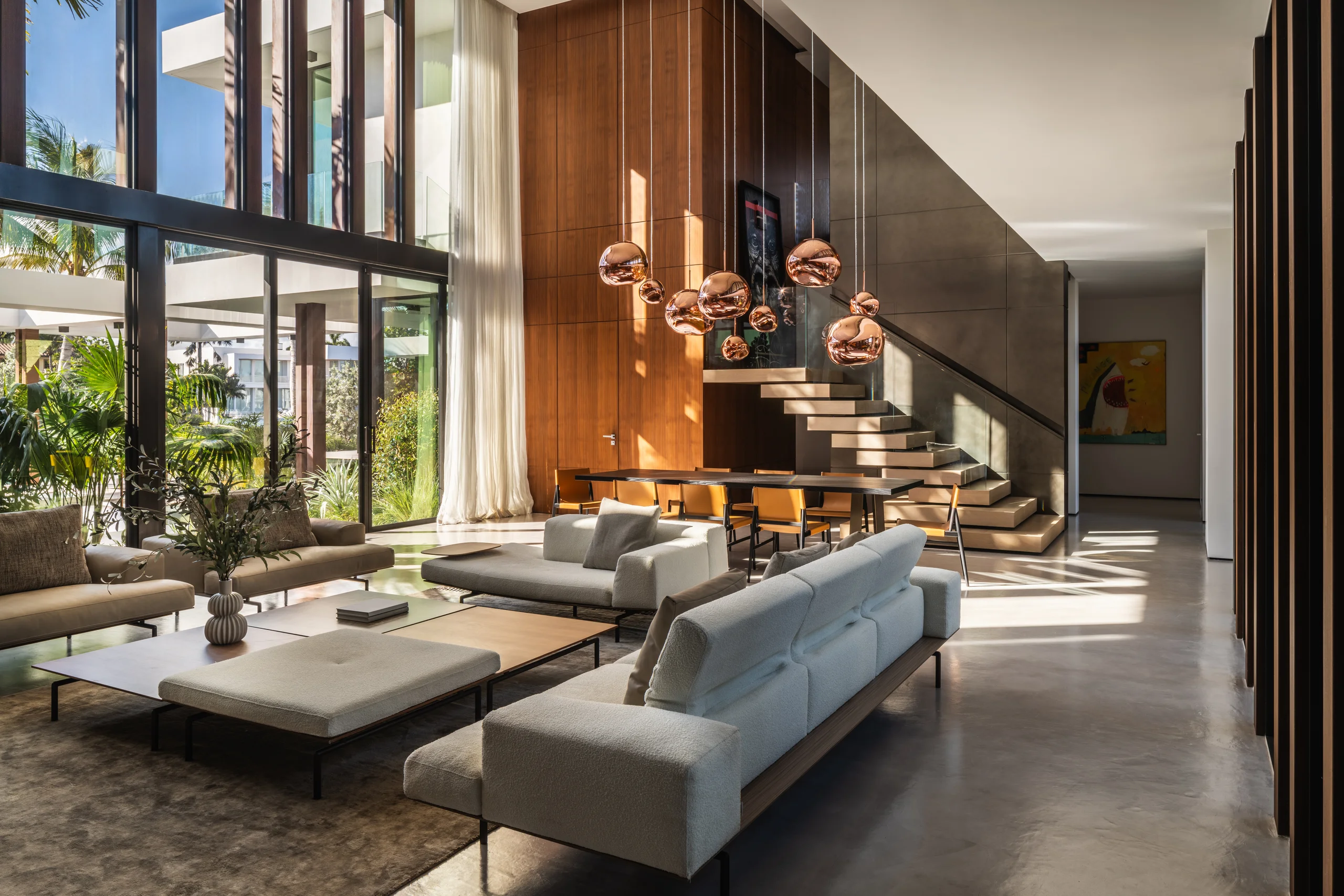 Living and dining area with a cascading copper globe pendant and a floating staircase, Spanish River Modern project by Dunagan Design.