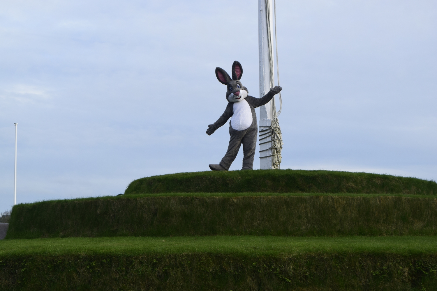 Truffles is stood ontop of Tynwald Hill on the Isle of Man, posing with his arms out next to a flagpole