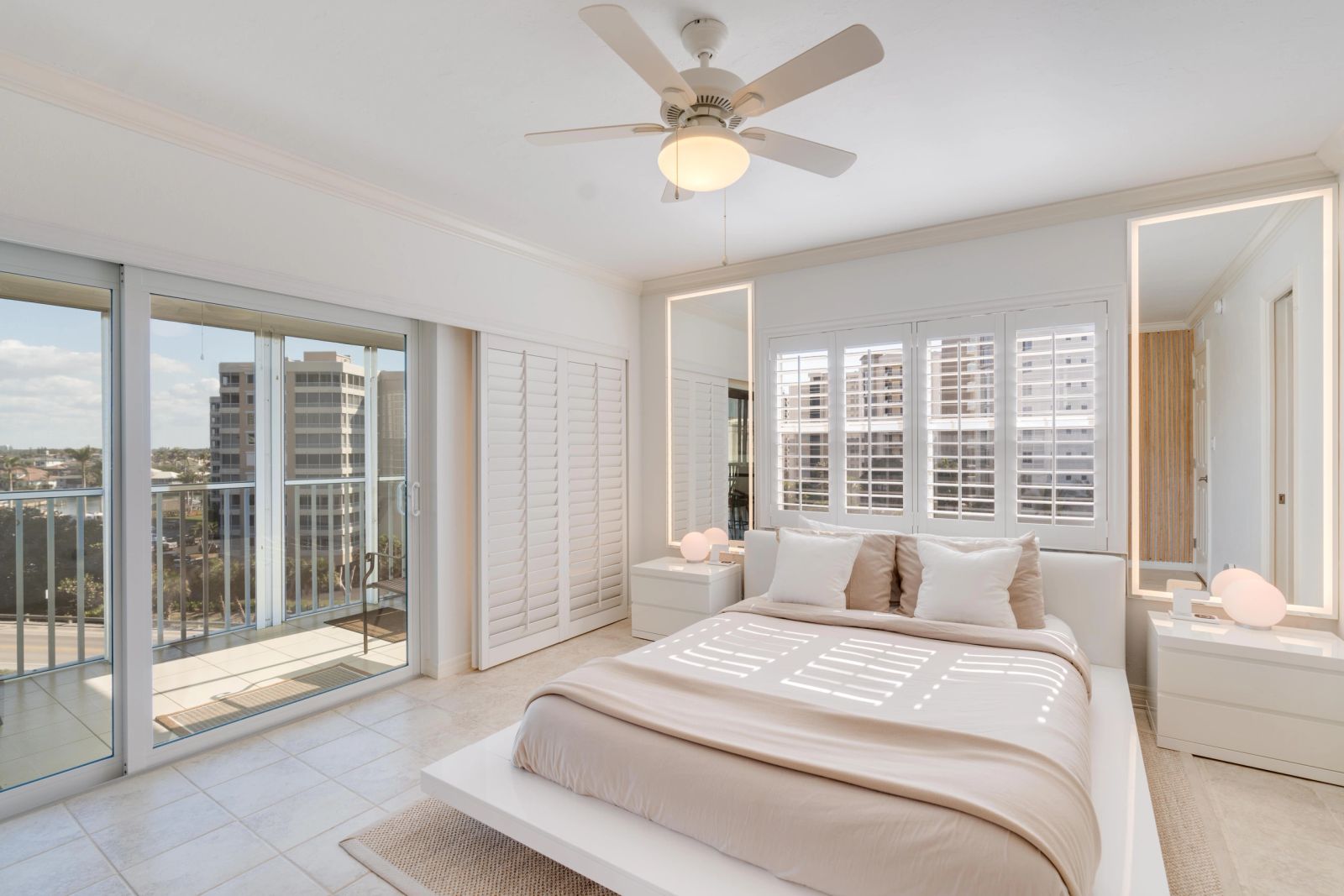 White bedroom with glazed doors and plantation shutters