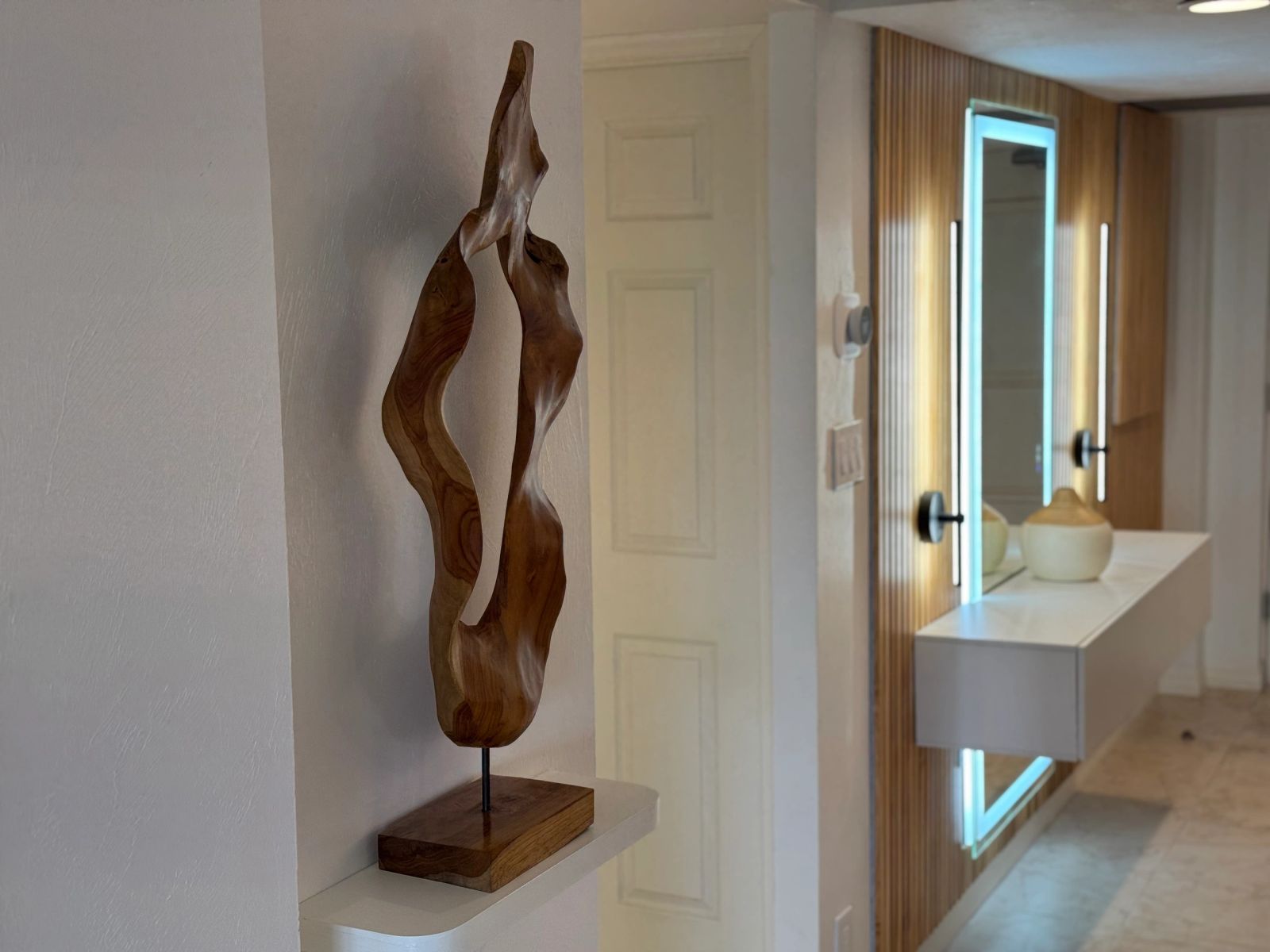 Abstract sculpture displayed beside a timber-framed mirror