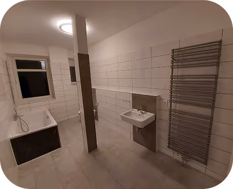 Modernes Badezimmer mit Badewanne, Waschbecken und Edelstahl-Handtuchheizkörper, weiß gefliest.