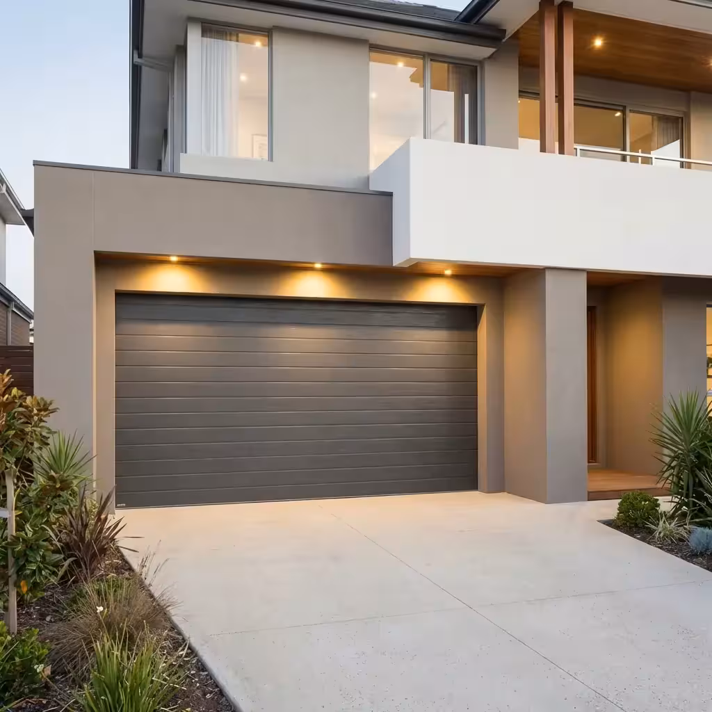 Modern gray sectional garage door with rectangular windows partially open on a residential driveway.