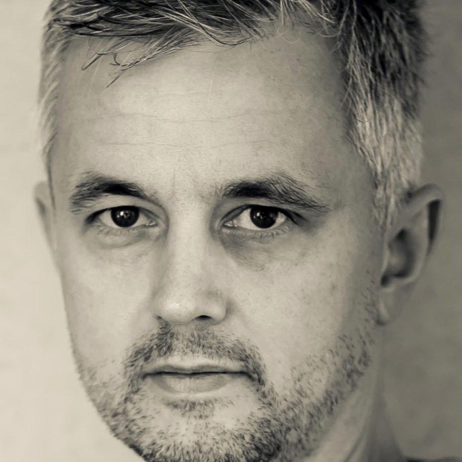 Close-up portrait of a middle-aged man with short gray hair and a trimmed beard in black and white.