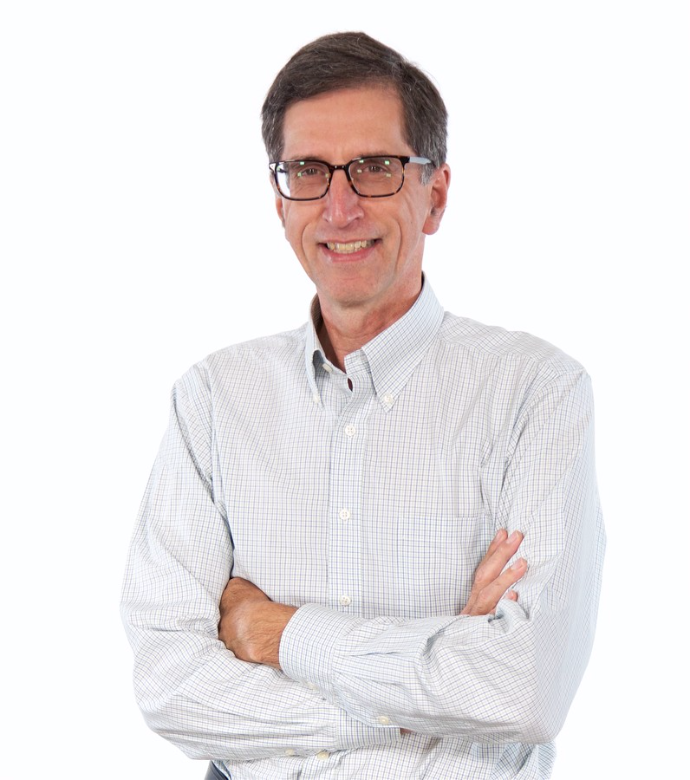 Smiling middle-aged man with glasses in a light checkered button-up shirt standing with arms crossed.