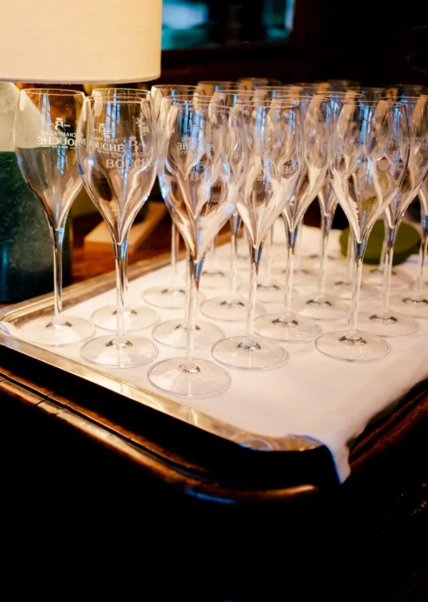 Verres à champagne vides alignés sur un plateau argenté avec une serviette blanche dans un cadre élégant.