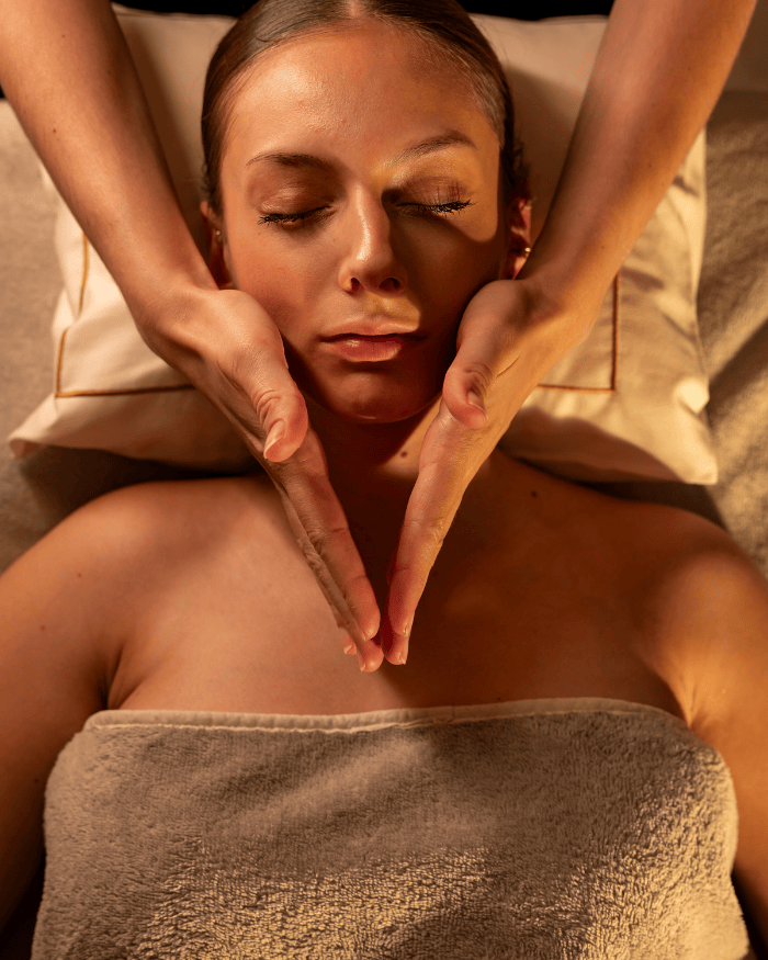 Gros plan d'une femme recevant un soin du visage relaxant ou un massage facial dans un spa.