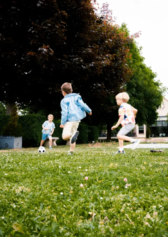 Children playing football in a garden during an outdoor activity.