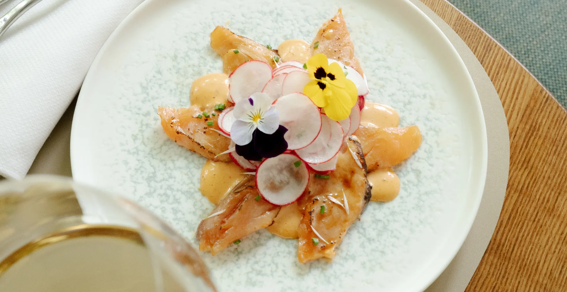 Piatto gourmet decorato con fiori commestibili durante un'esperienza culinaria della Beauvallon Collection.