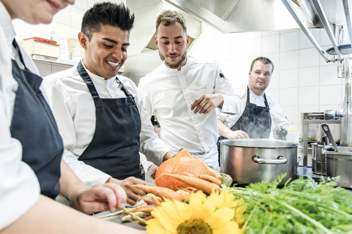 Chef e team di cucina che preparano prodotti freschi in un locale gastronomico appartenente al gruppo Beauvallon Collection.