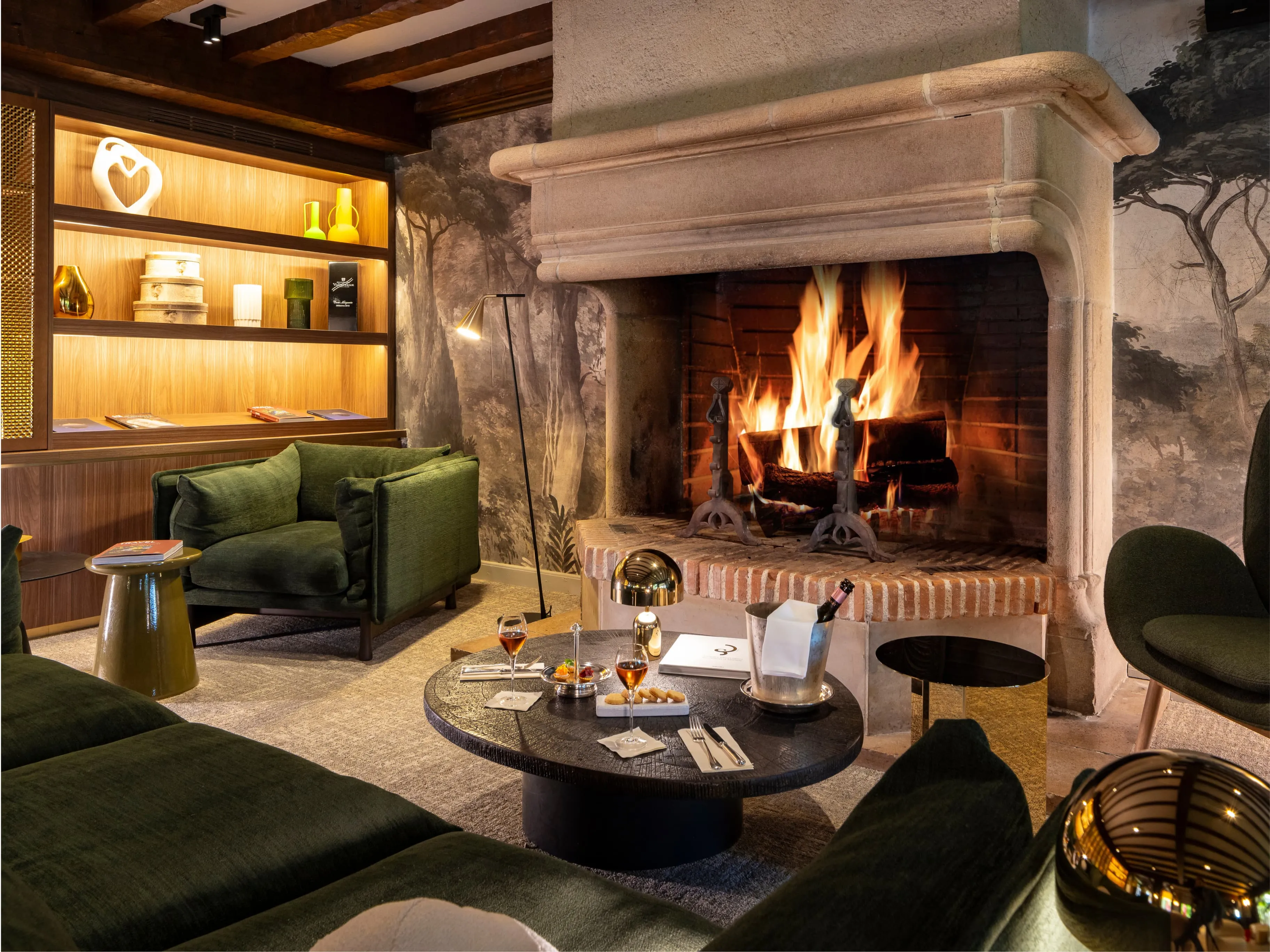 Salotto accogliente con camino presso l'Hostellerie La Briqueterie & Spa, un affascinante hotel appartenente al gruppo Beauvallon Collection in Champagne vicino a Épernay.