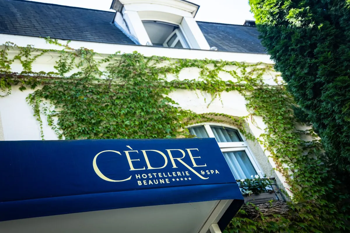 Facciata dell'Hostellerie Cèdre & Spa Beaune immersa nel verde in Borgogna.