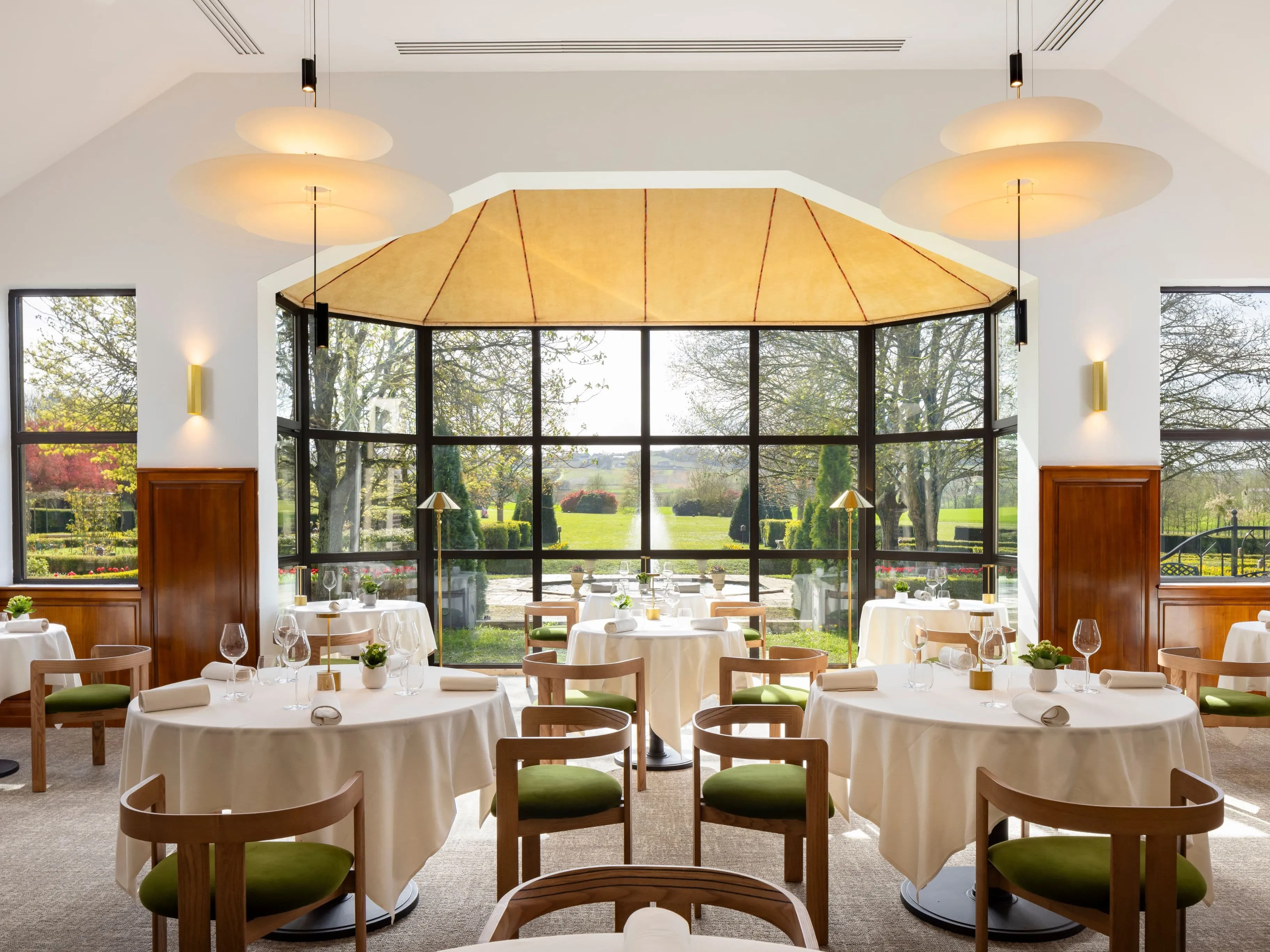 Luminosa sala ristorante con vista sui giardini dell'Hostellerie Briqueterie en Champagne.
