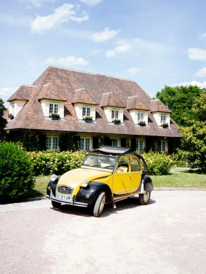 Yellow Citroën 2CV in front of the Hostellerie Briqueterie in Champagne.