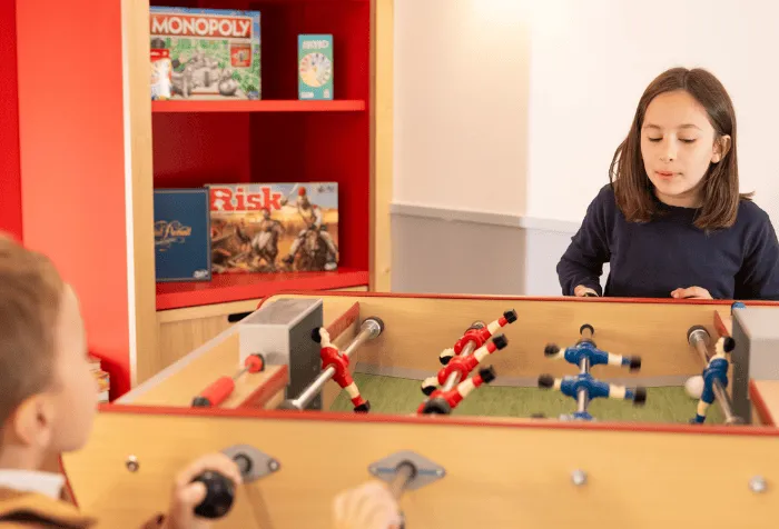Children playing table football in a game room.